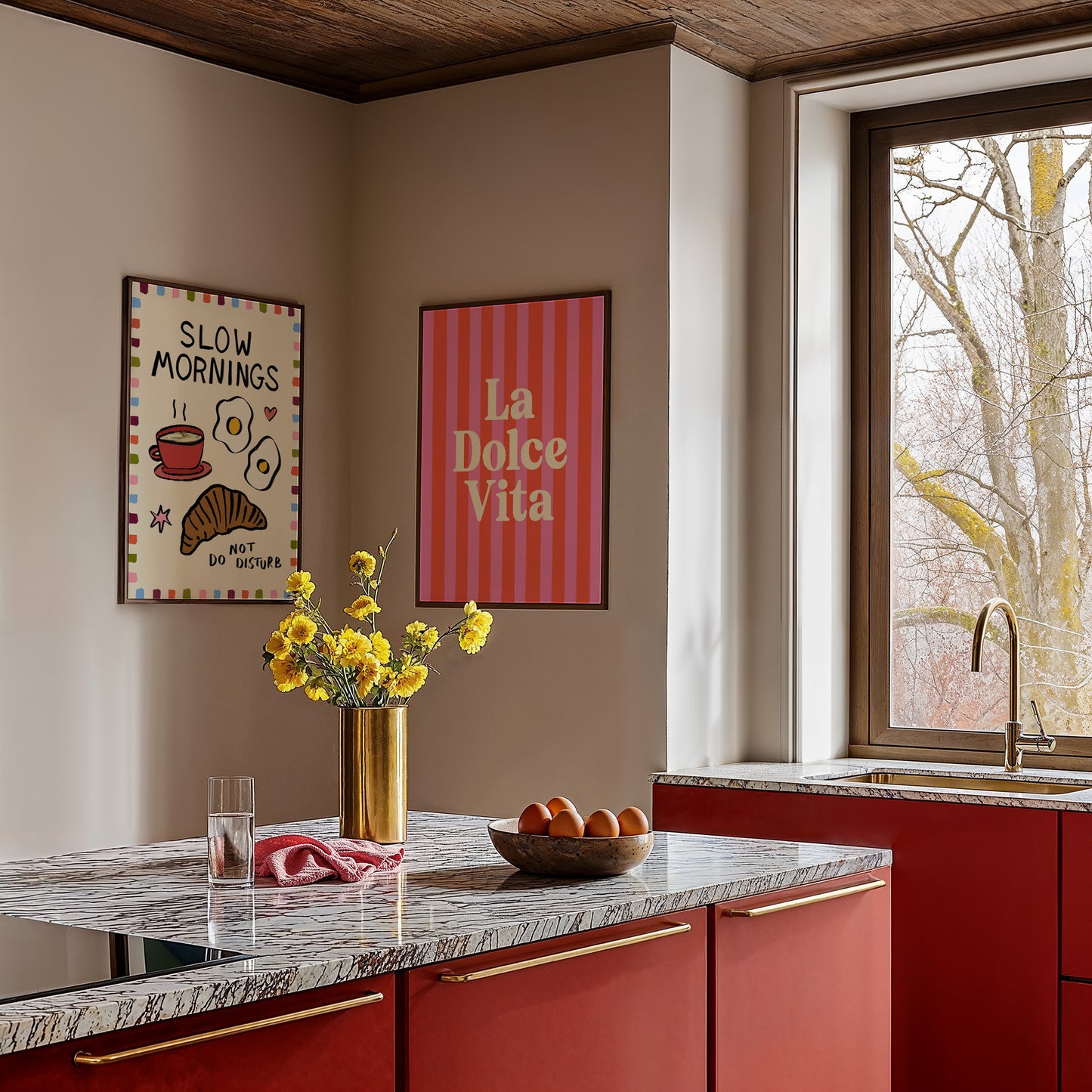 Modern kitchen with red cabinets, marble countertop, and decorative wall art.