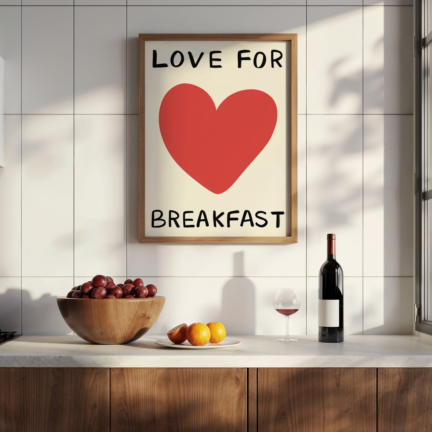 Framed artwork with a red heart and text on a kitchen wall, featuring a bowl of fruit, wine bottle, and glass.