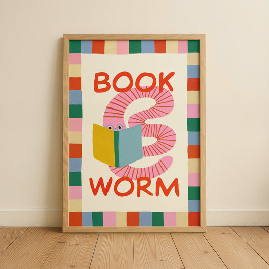 Framed artwork with a colorful worm reading a book design on a beige wall.