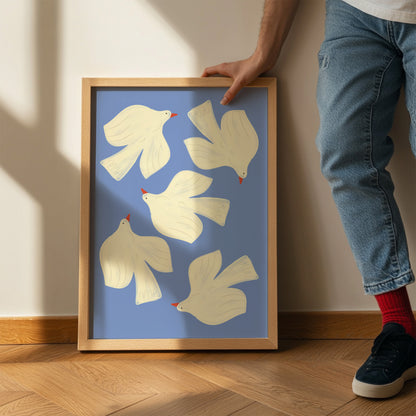 Framed artwork of white birds on a blue background, held by a person.