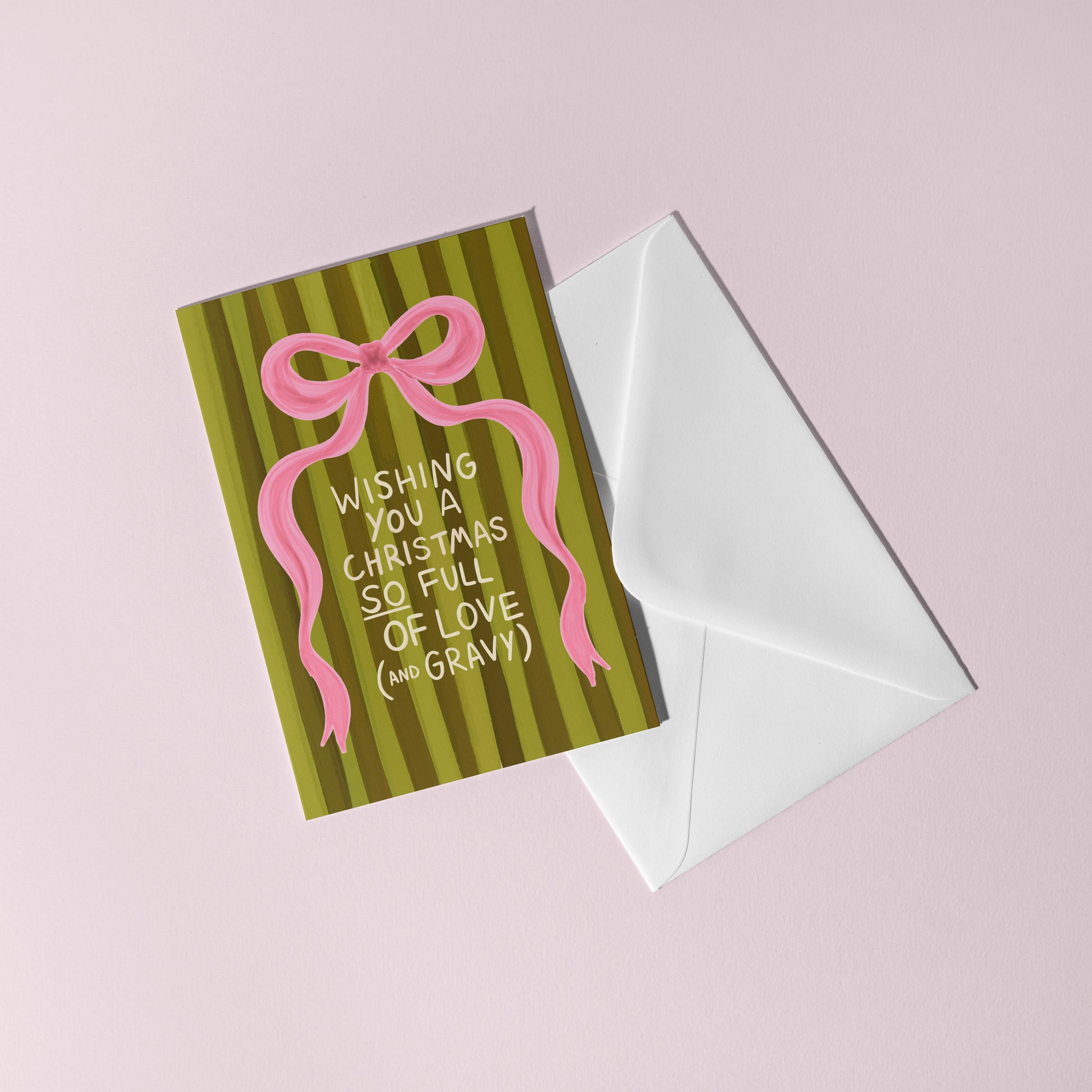 Greeting card with pink bow and text on green striped background, white envelope on pink background