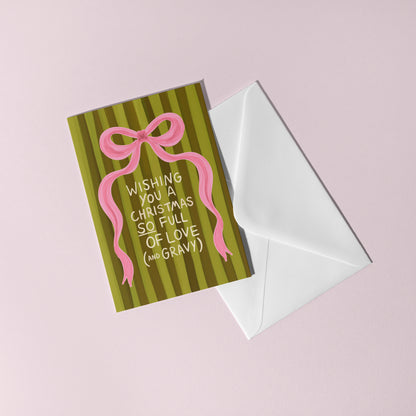 Greeting card with pink bow and text on green striped background, white envelope on pink background