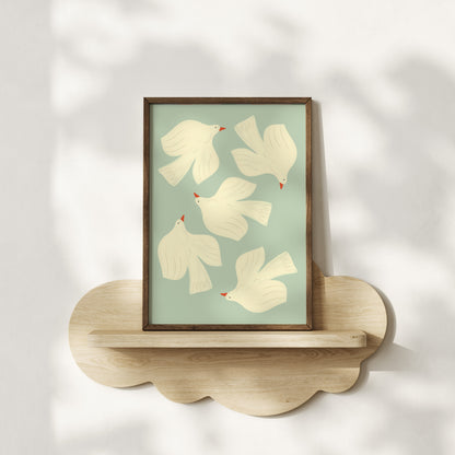 Framed artwork with white birds on a light green background, displayed on a wooden shelf.
