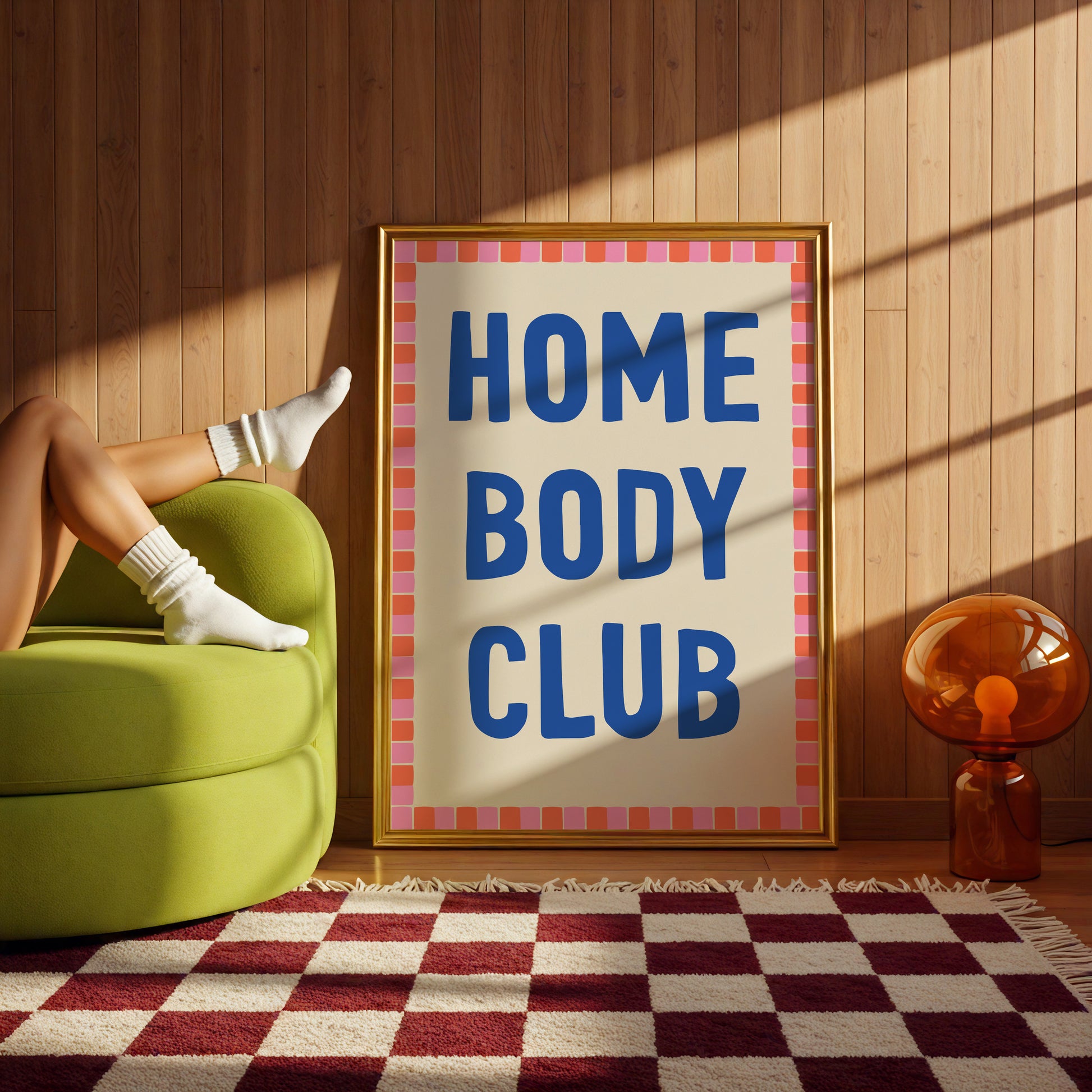 Poster with 'HOME BODY CLUB' text in a room with a green chair and checkered rug.