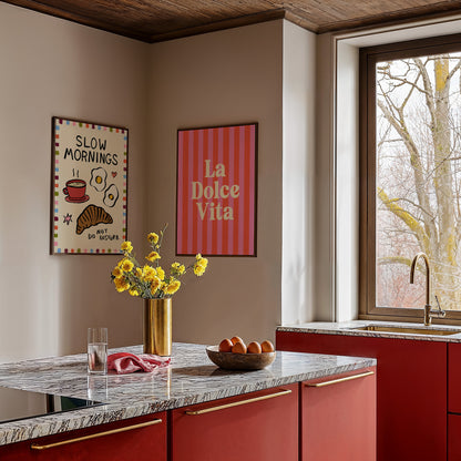 Modern kitchen with red cabinets, marble countertop, and decorative wall art.