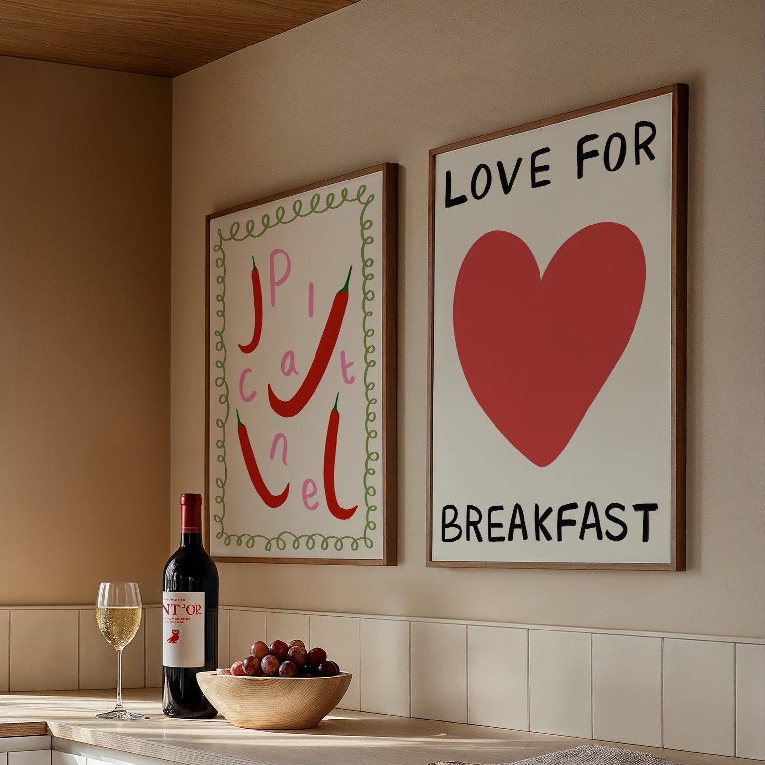 Modern kitchen with wine bottle, grapes, and two framed artworks on the wall.