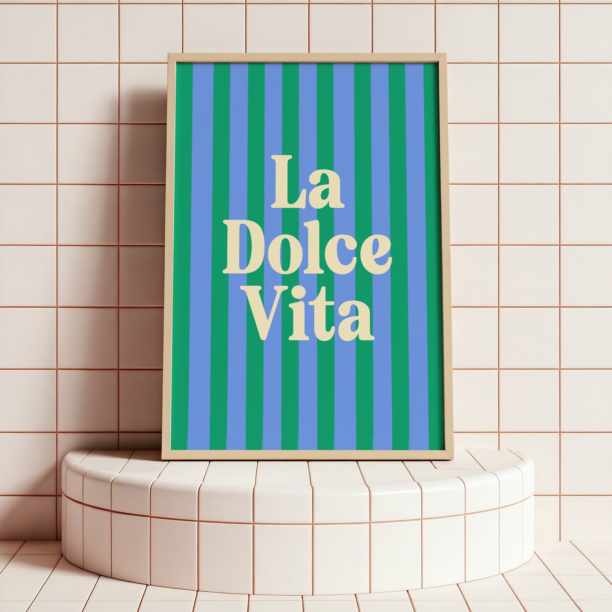 Framed artwork with 'La Dolce Vita' text on a striped background, placed on a tiled surface.