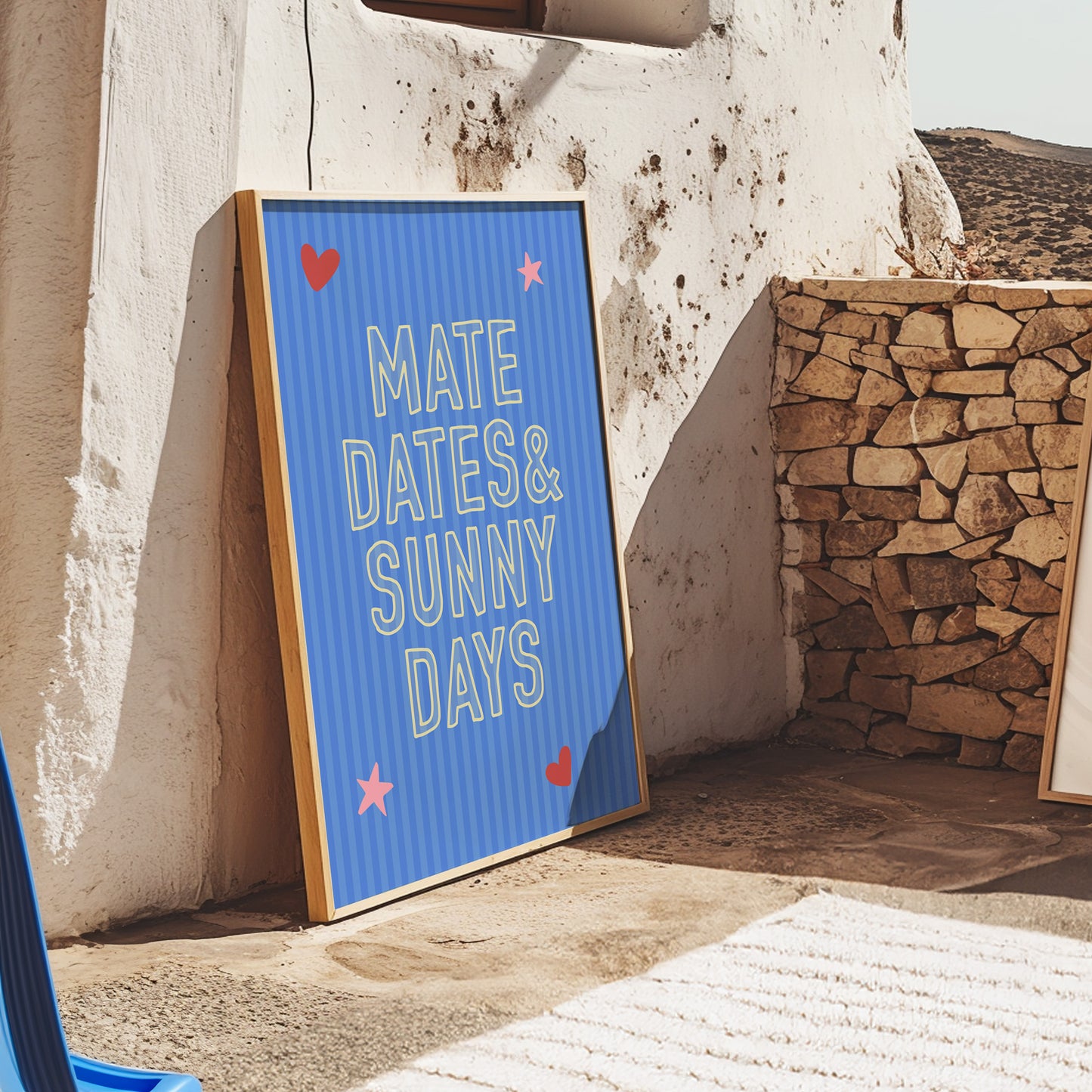 Blue framed sign with text 'MATE DATES & SUNNY DAYS' leaning against a stone wall.