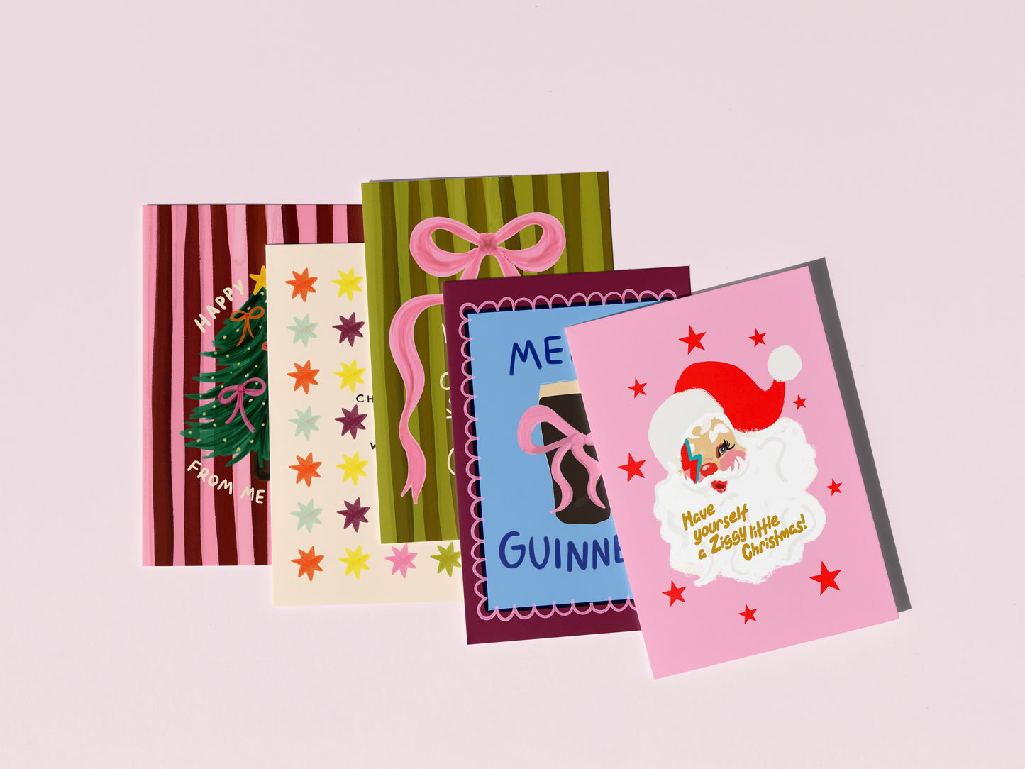 Collection of Christmas-themed greeting cards on a light pink background