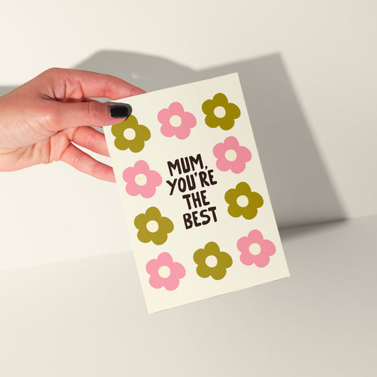 Hand holding a card with floral design and text on a neutral background
