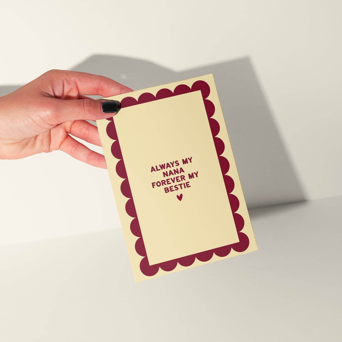 Hand holding a card with text 'Always my mum, forever my bestie' on a plain background