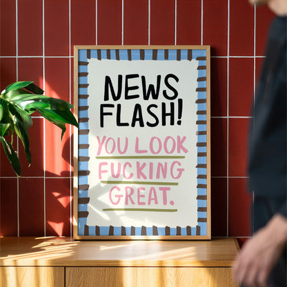 Framed poster with motivational text on a wooden surface against a red tiled wall.